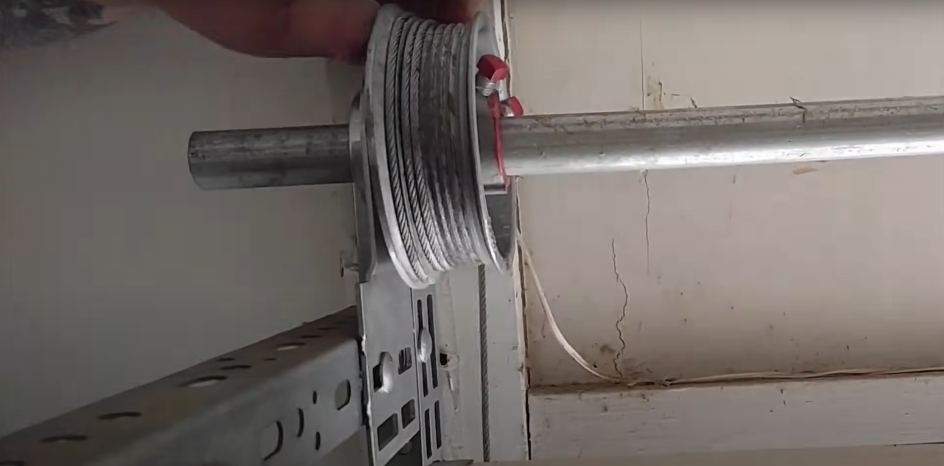 A technician in uniform repairing a frayed garage door cable with specialized tools.