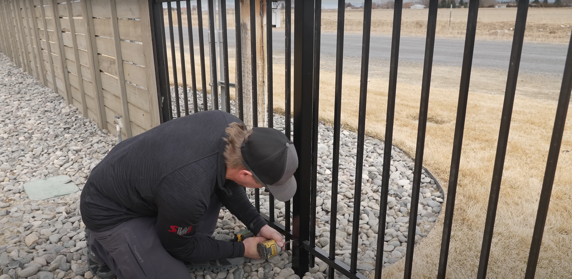A technician performing professional gate repair on a residential driveway.