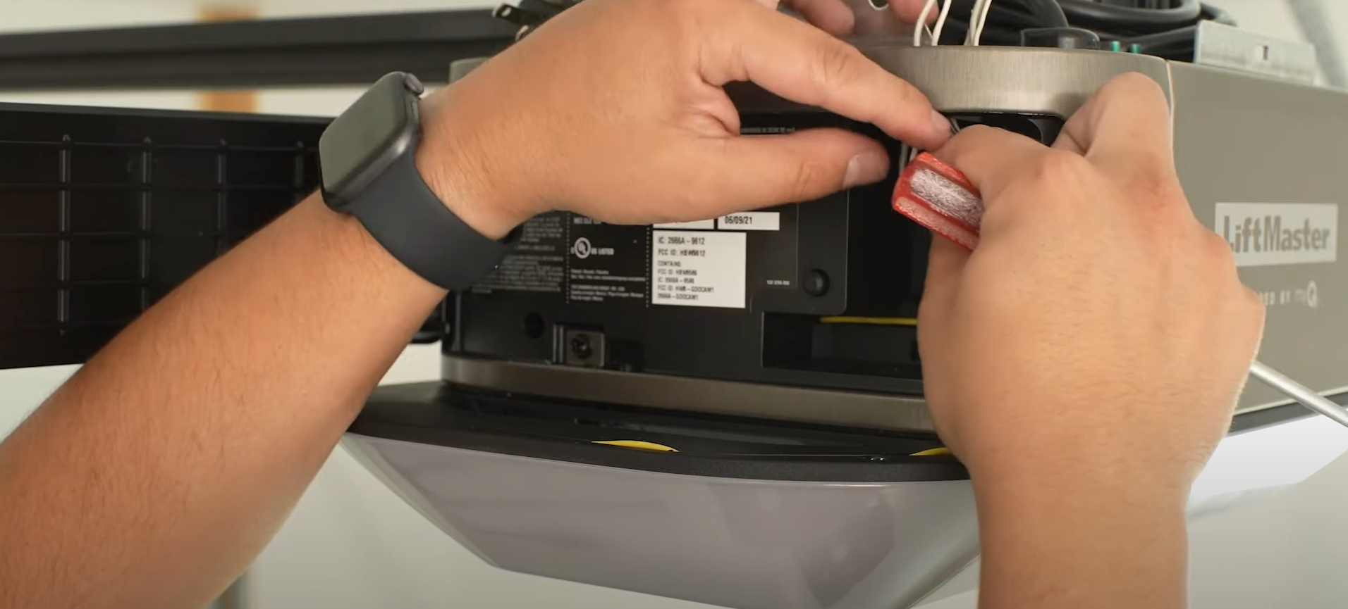 Alt text: A technician performing a garage door opener repair.