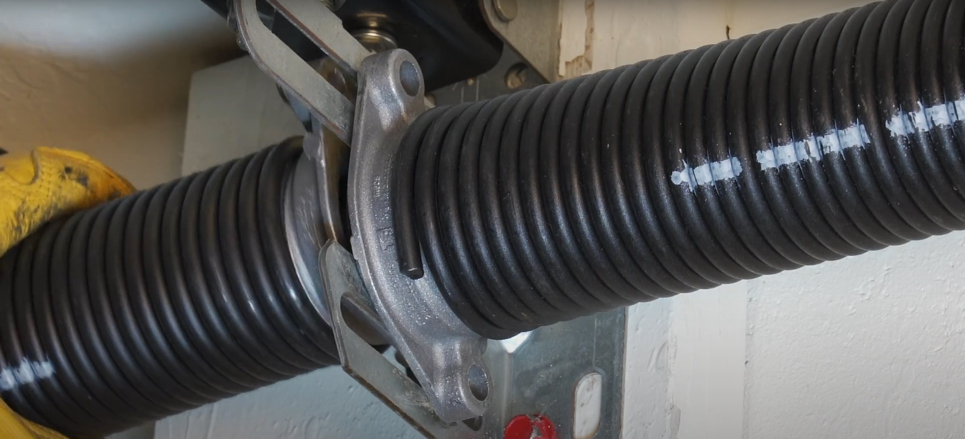 A close-up of a high-tension steel garage door spring installed on a residential door system.