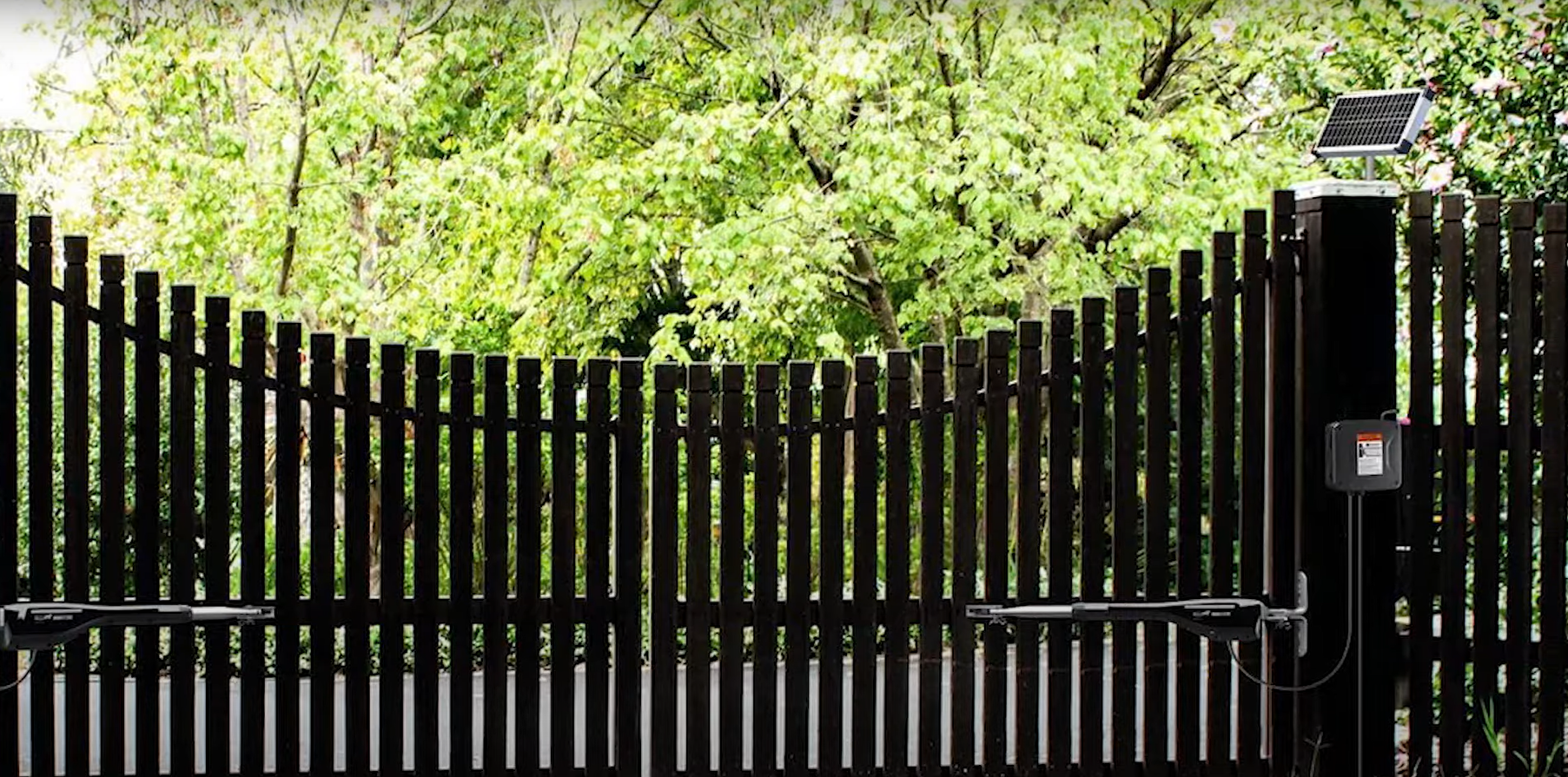 A commercial driveway gate being repaired by a technician.